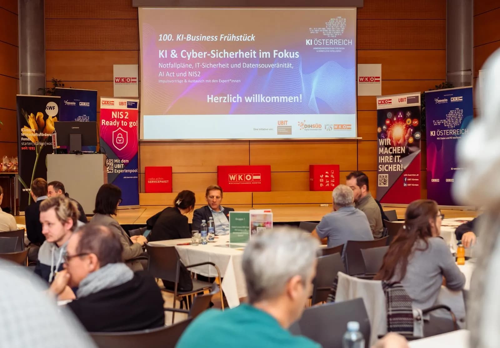 Voll besetzter Saal beim WKO Business-Frühstück, auf der Leinwand „100. KI-Business Frühstück – KI & Cyber-Sicherheit im Fokus“
