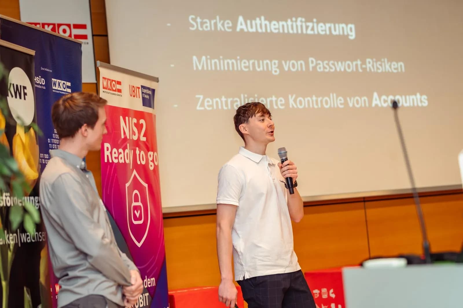 HoliSec-Gründer mit Mikrofon bei einem Vortrag zu NIS 2 beim WKO Business-Frühstück, dahinter das Roll-up „NIS 2 – Ready to go“